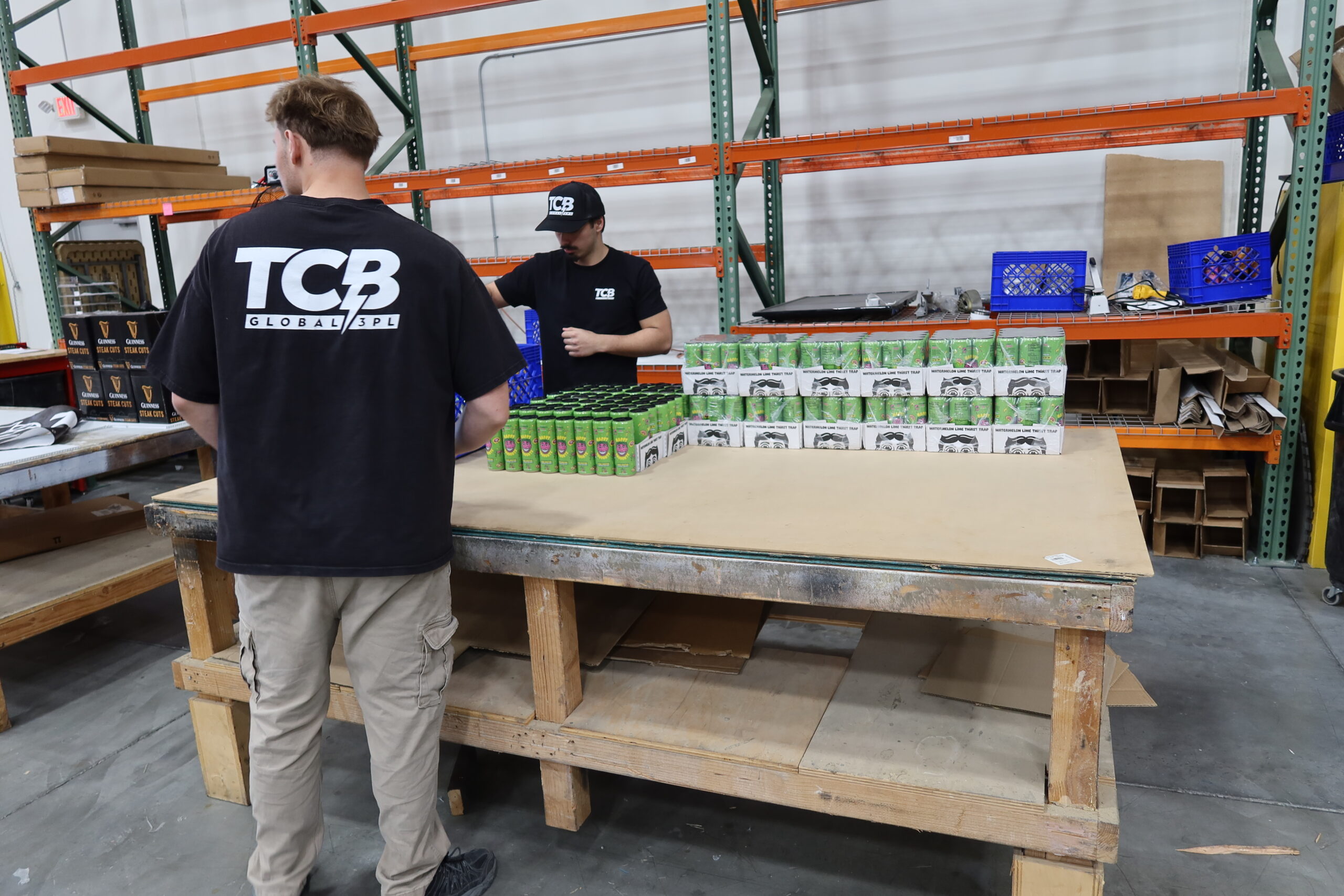 TCB Logistics employees working at storage and fulfillment with a stack of canned drinks.